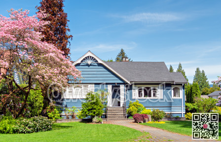 Neat residential house with green lawn in front on blue sky background