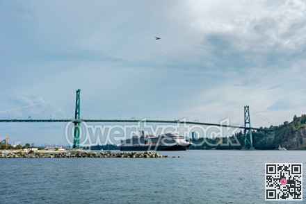 View of ocean harbor with huge ocean cruise liner passing Lion Gates Bridge