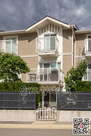 Residential condo building with fenced front yard on stormy sky background