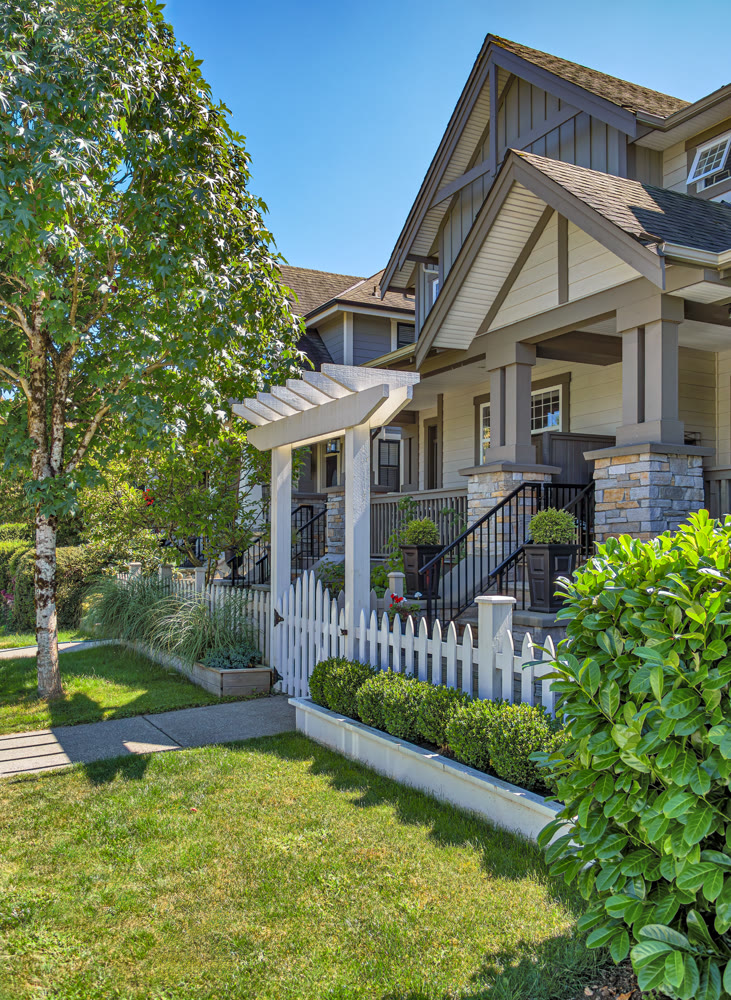 The porch of a nice residential house entrance with wooden gate and white birch in front