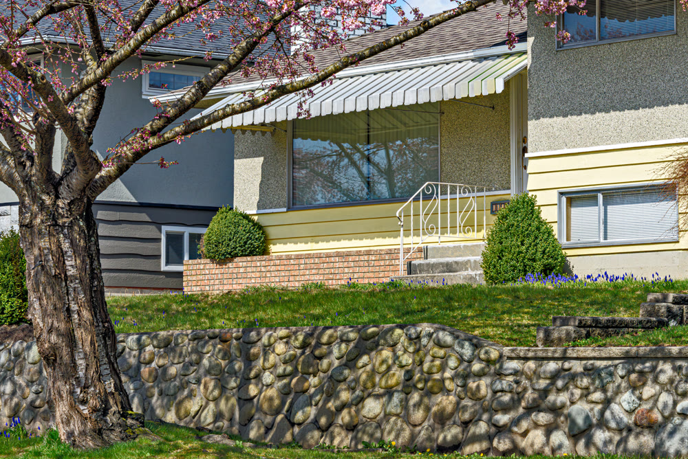 Entrance of the family house under the canopy with front lawn on the land terrace
