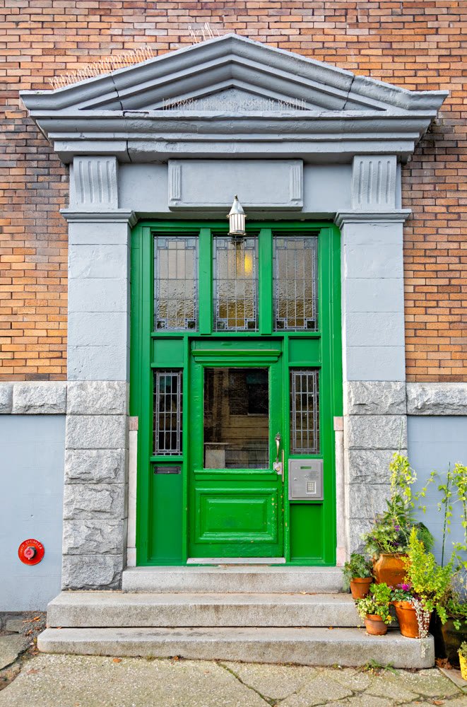 Entrance of old residential building in Vancouver decorated with flower pots