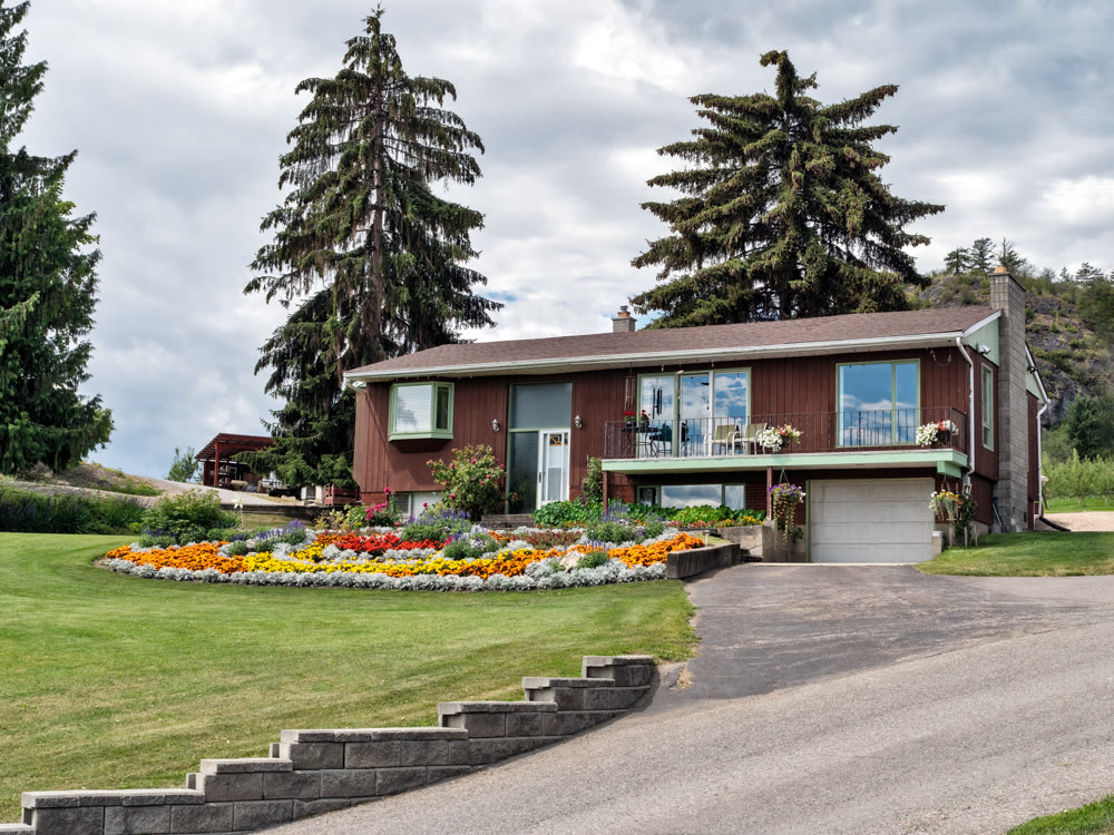 Old residential house in Canada with big flower bed on the front yard
