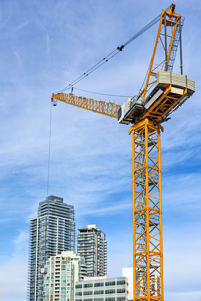 High-attitude crane and high-rise residential buildings on blue sky background