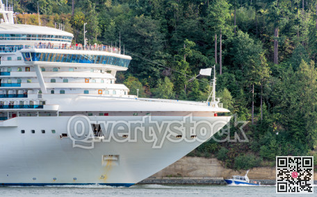 Huge white cruise liner passing by Stenley Park in Vancouver, Canada