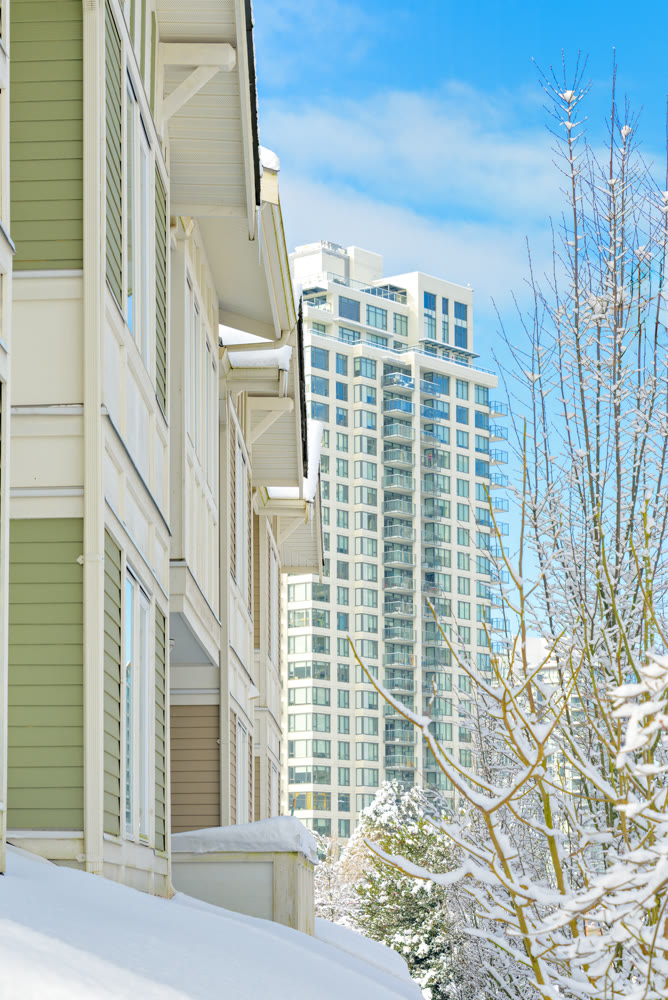 Residential townhouses and high-rise building on bright winter day