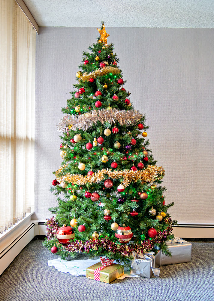 Tall Christmas tree decorated with balls, lights, and glittering firs