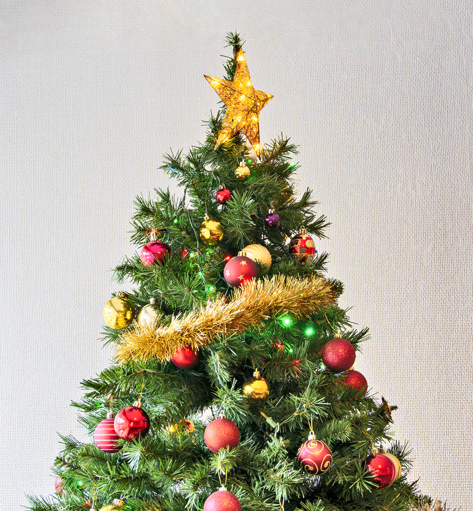 Golden star and colourful balls with color electtric lights decorating top of artificial Christmas tree