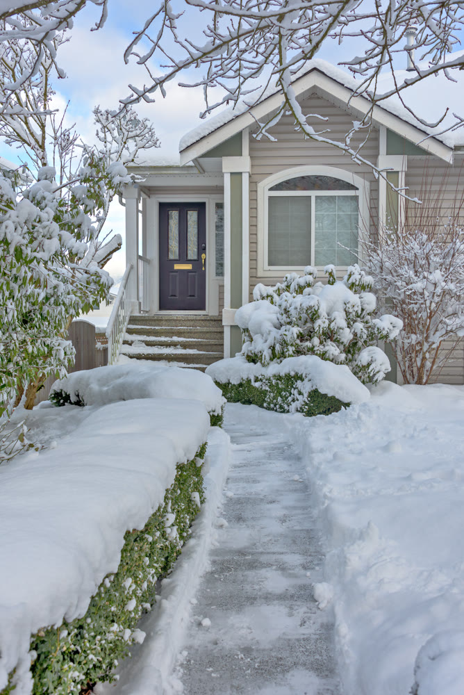 Cleaned pathway to the family residential house over front yard in snow