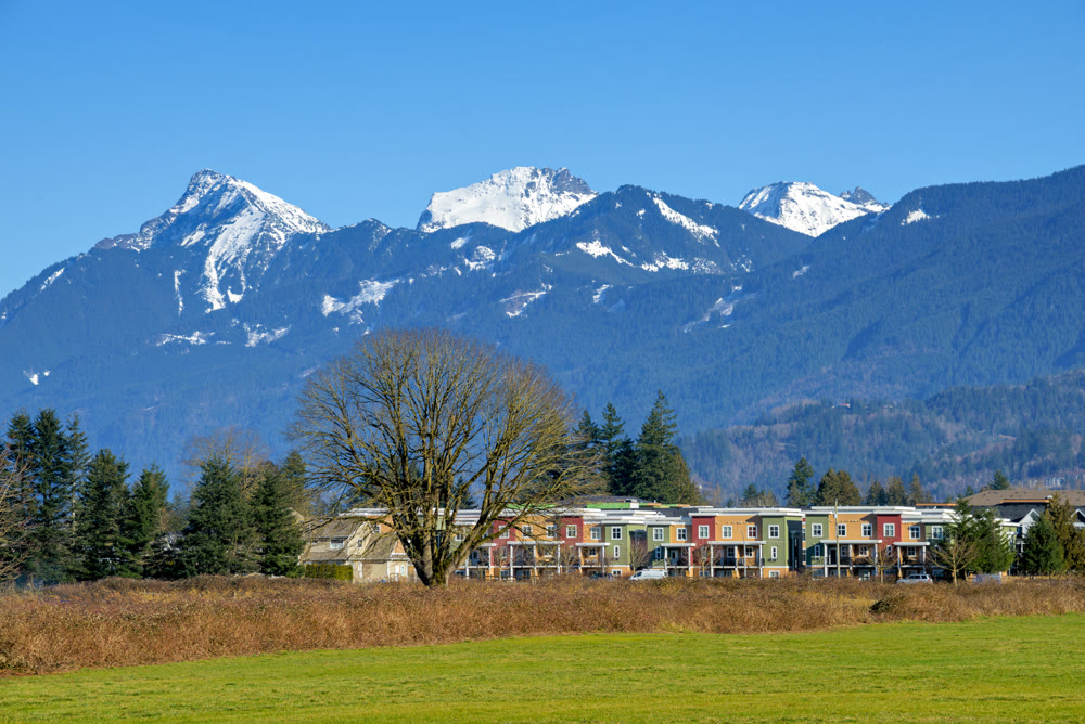 New residential townhouses on blue sky and mountain background. Winter season in Fraser valley, British Columbia