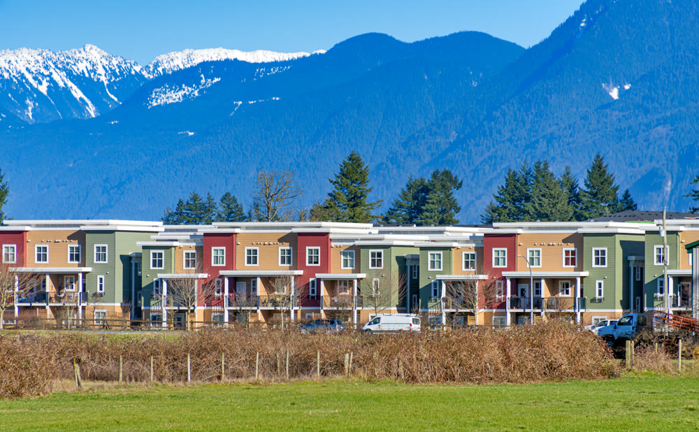 New residential townhouses on blue sky and mountain background. Winter season in Fraser valley, British Columbia