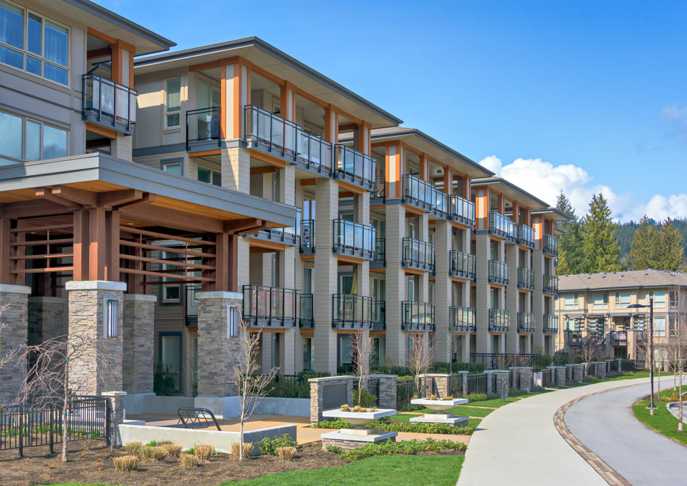 New residential apartment building with walkway and bike route in front on sunny day in British Columbia, Canada