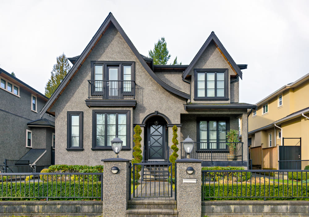 Gloomy residential house with metal fence in front on overcast sky background