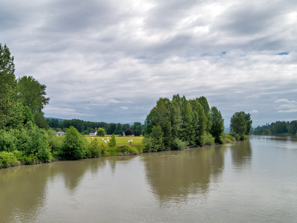 A picturesque riverside scene with a white church on the shore.
