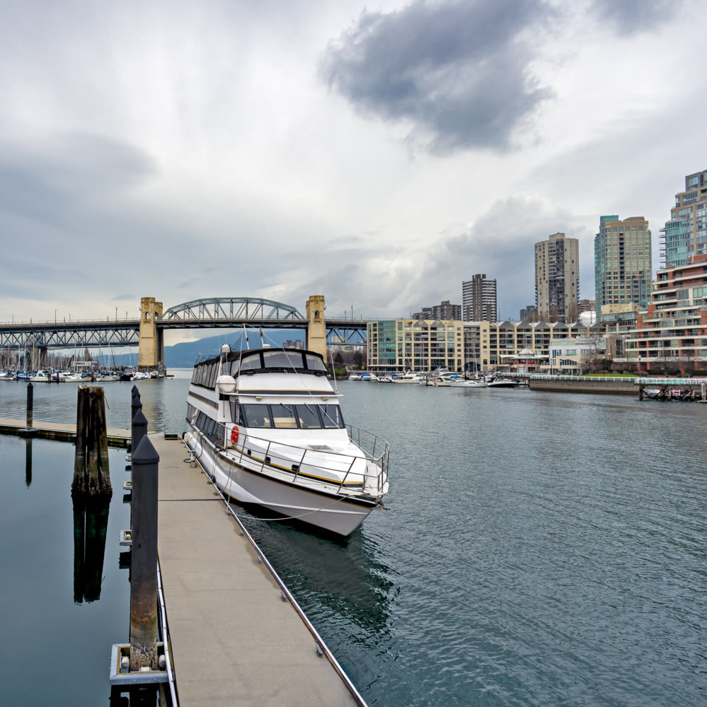 Tourist tour boat moored at the pier with Burrard bridge and Vancouver downtown on the background