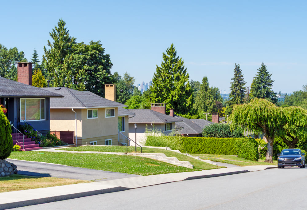 Street of residential houses with a car parked on side. Residential area with Metrotown view