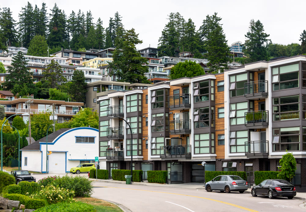 A perfect neighborhood. Uphill residential area with cars parked on the streets around the building
