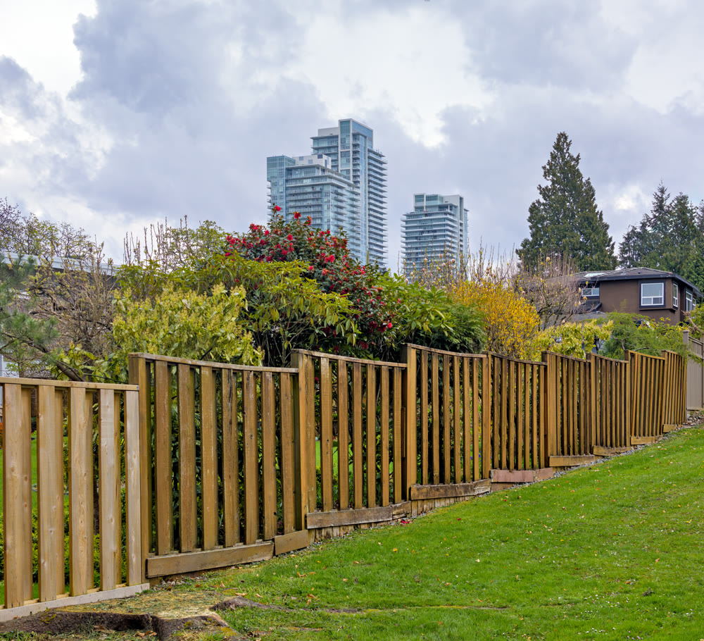 Wooden fenc in residential area with high-rise buildings on cloudy sky background