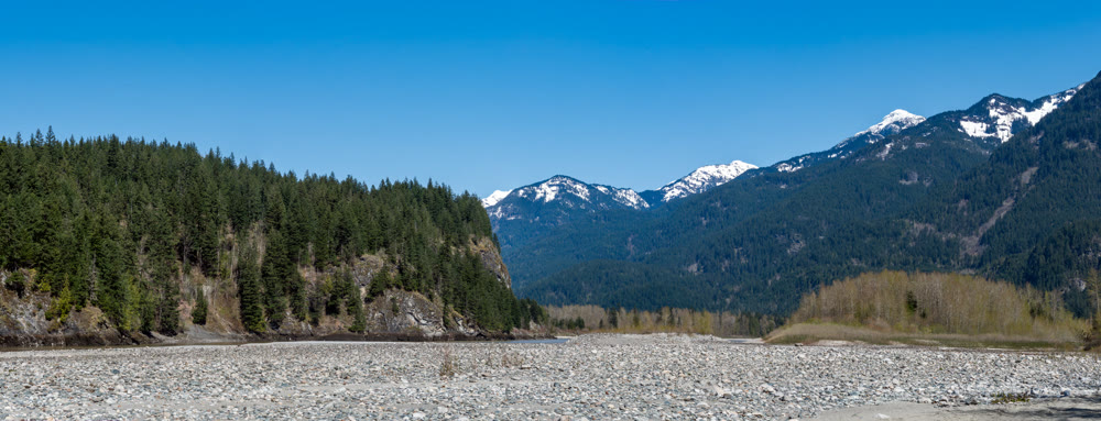 Panoramic view of Rocky mountains in British Columbia with drying-up river bed in front