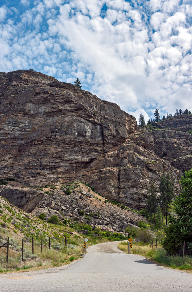 Gated gravel road leading to the mounain area in Canada. Vertical panorama