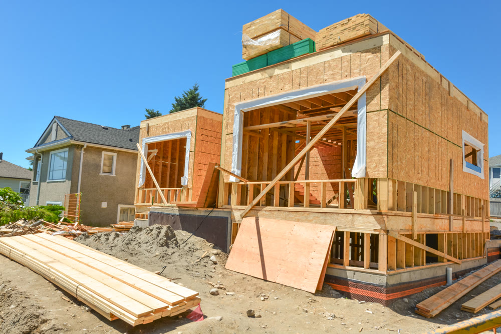 New family home under construction with stacks of 2x4 timber boards on the top
