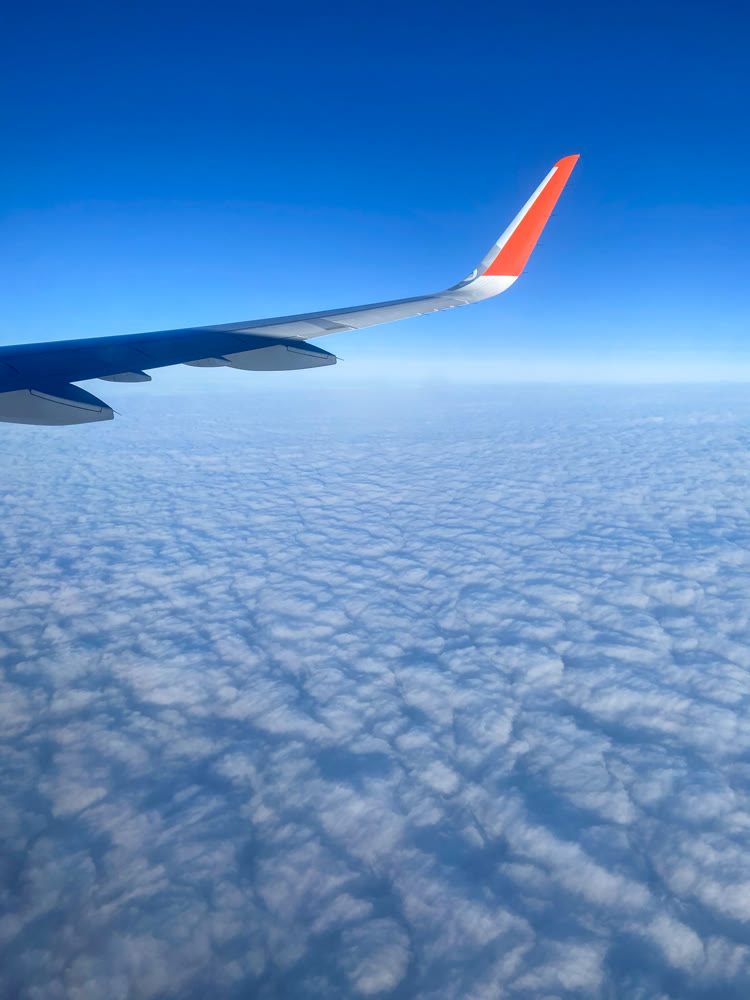 Wing of an air liner on blue sky and white clouds background