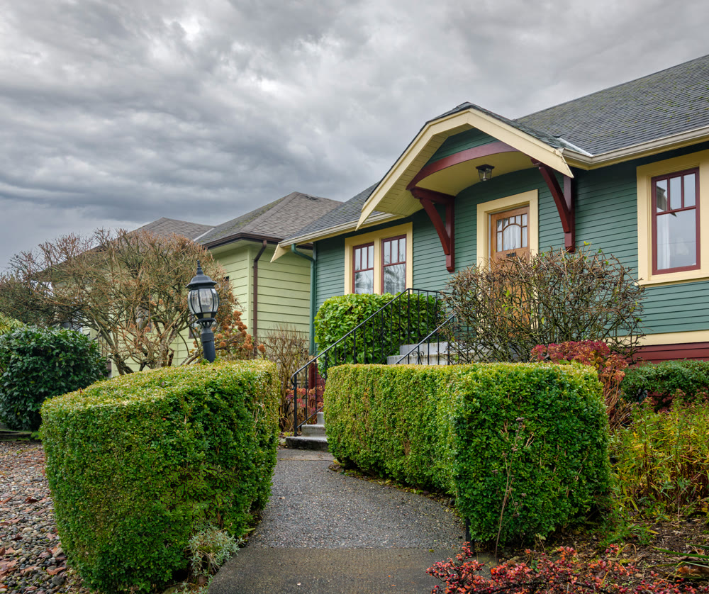 Hadge row fenced pathway and stairway of family residential house on overcast sky background