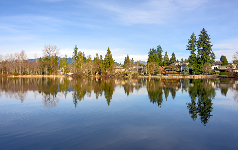 Winter cityscape and a park on a lake shore with reflection in the water