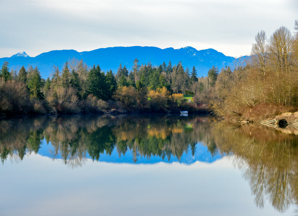 Autumn landscape scene with river, mountains and boat in a quiet factory