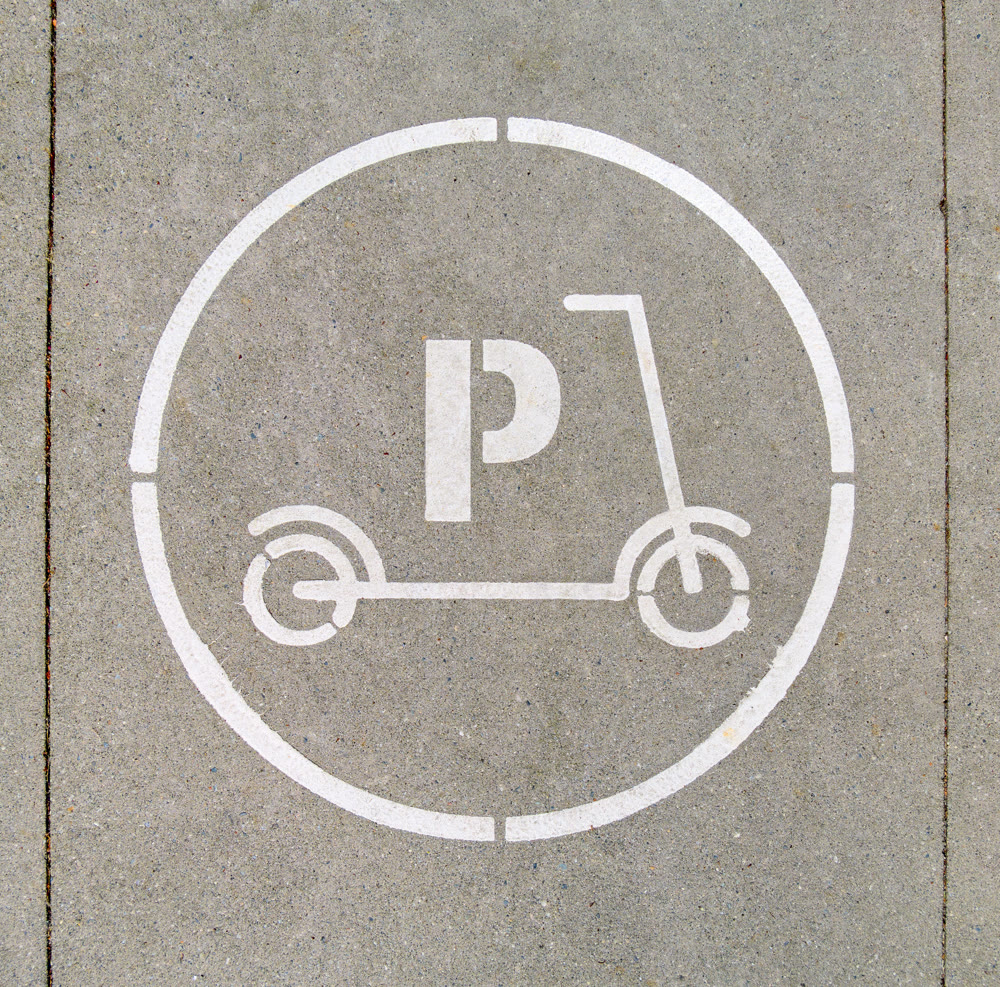 Electric scooter parking stall sign on concrete pavement surface