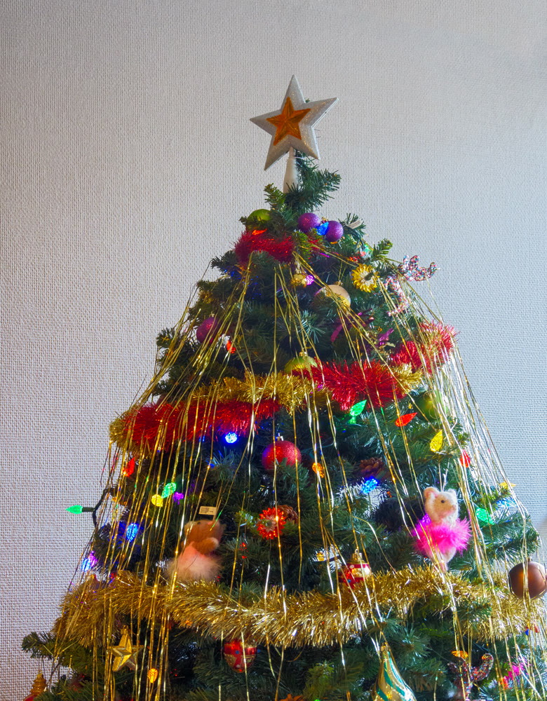 White-golden star and colourful balls with color electtric lights decorating top of Christmas tree