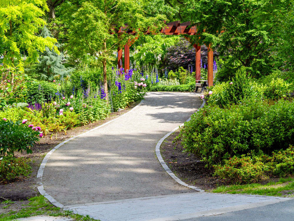 Gravel pathway to the entrance of small city park on sunny summer day