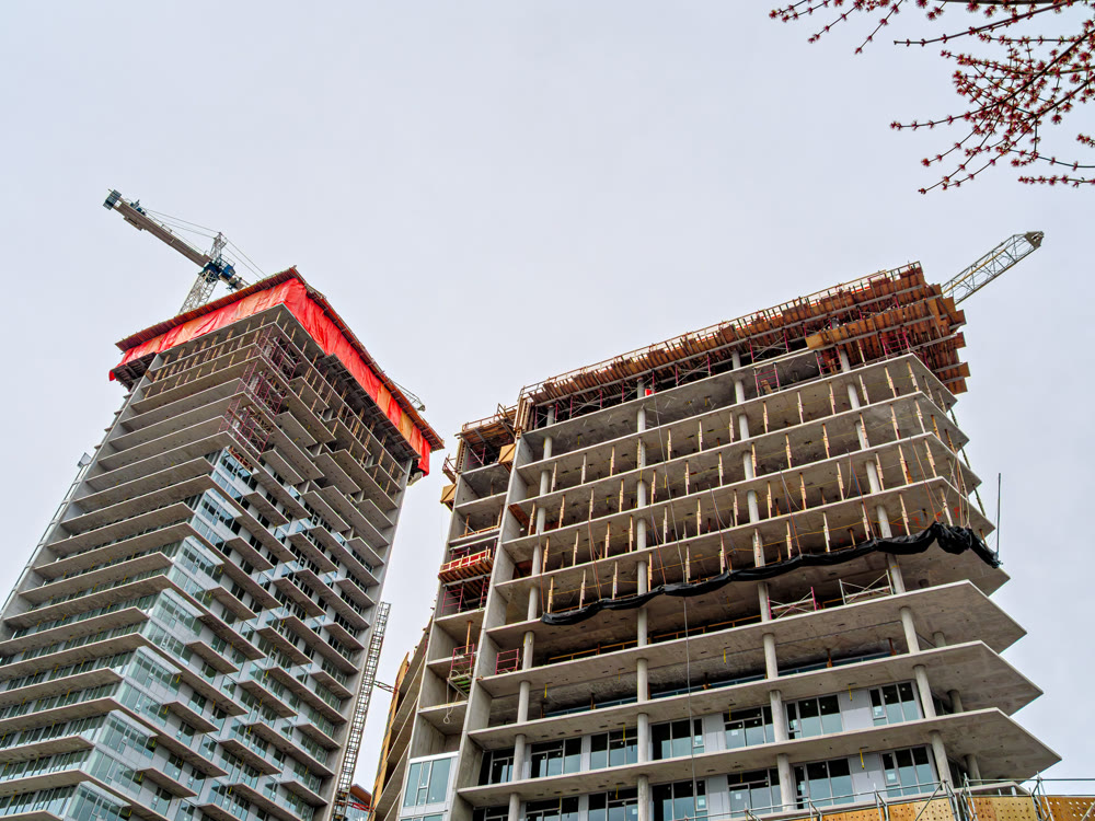 High rise monolith concrete buildings with the cranes above