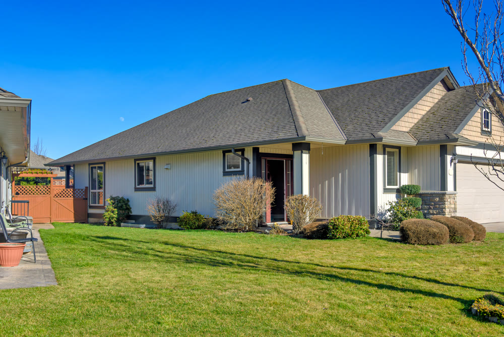 Entrance of residential house with green lawn on the front yard on blue sky background