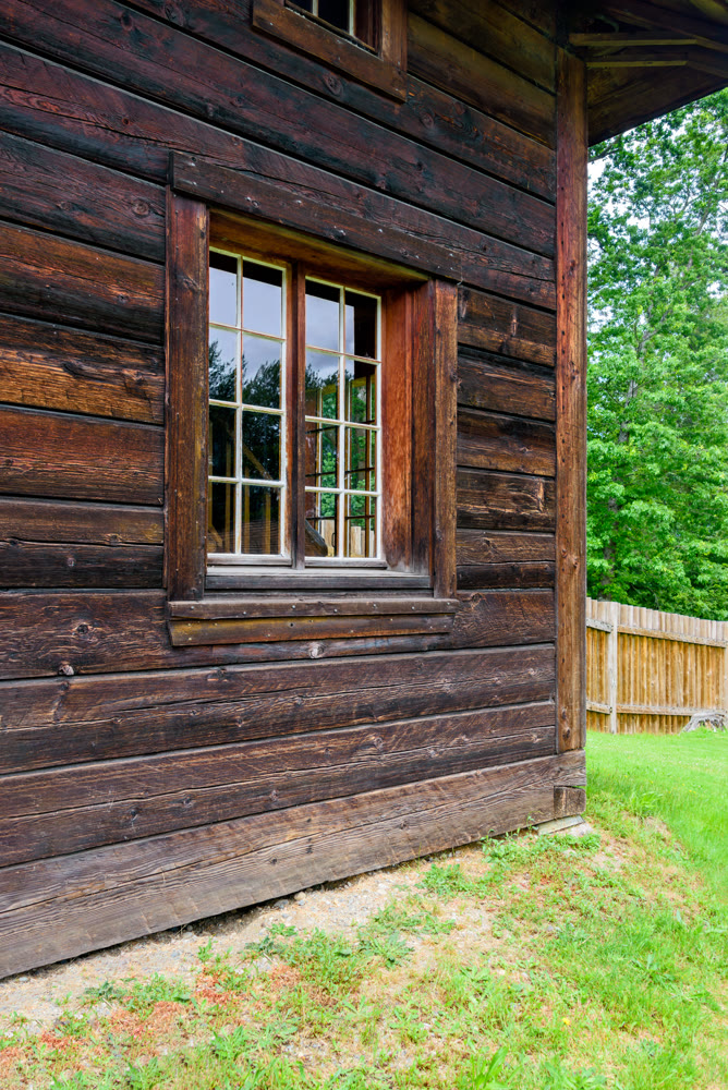 Corner of the building with window made of dark wooden beam