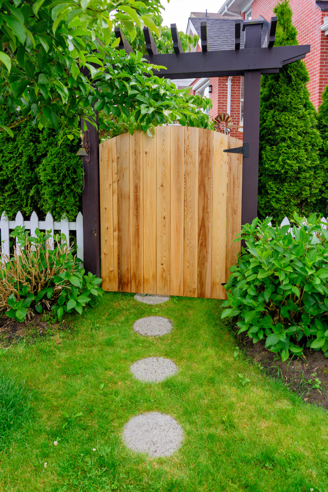 Unpainted wooden gate of residential house entrance with round pathway tiles