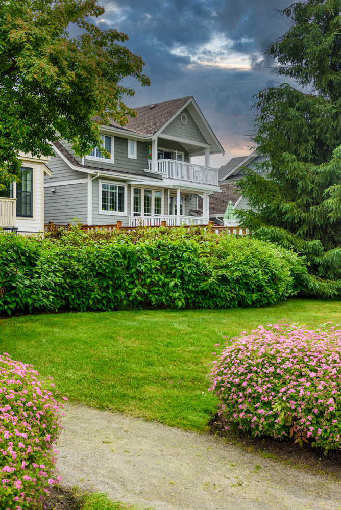 Residential family house with gravel pathway along side on cloudy sky background