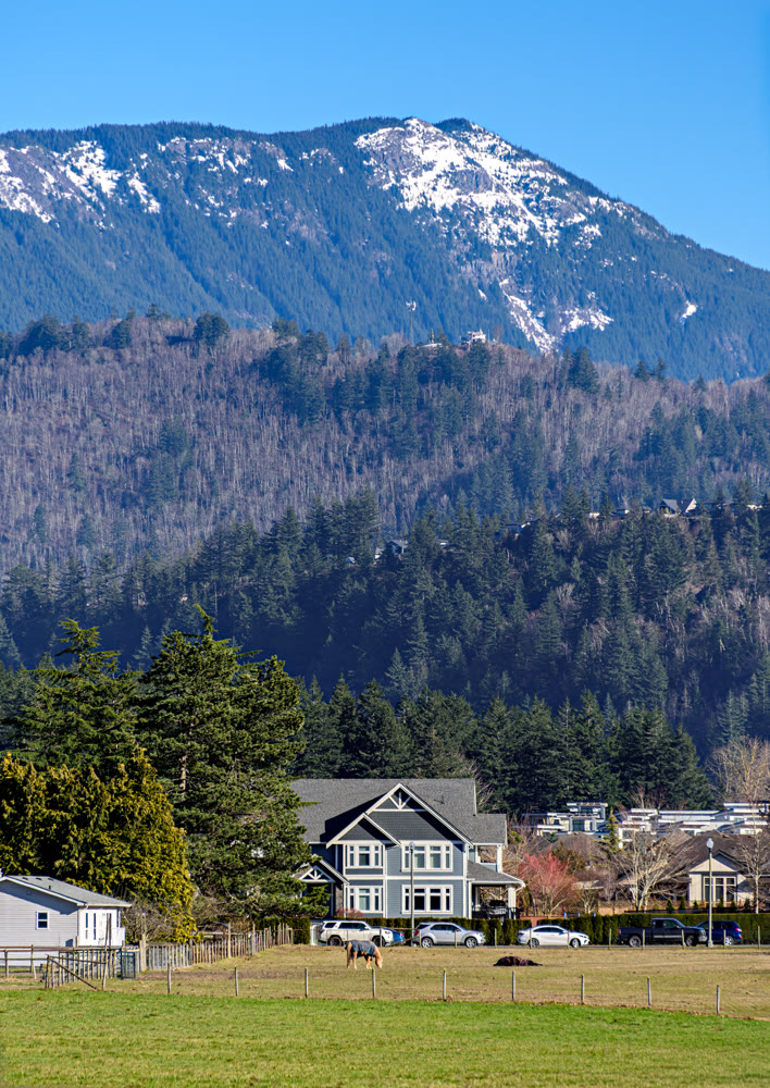 Residential houses on high mountain background. Winter season in Fraser valley, British Columbia