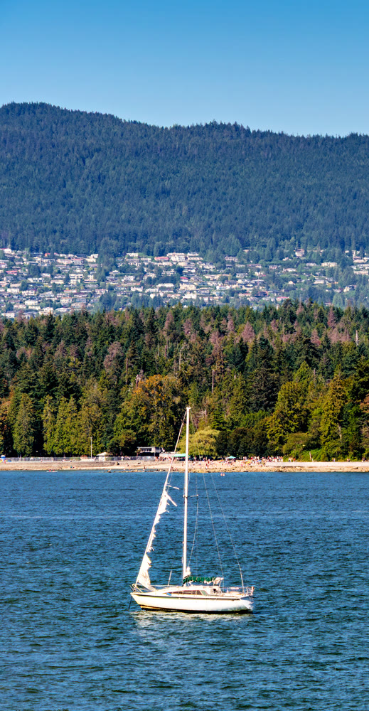 Sailing yacht with ruptured sail in emergency anchored in English bay in Vancouver