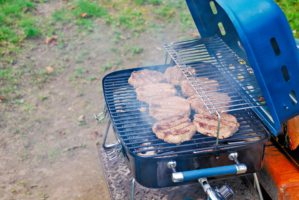 Grilled Burger Patties Sizzling on a Portable Barbecue Outdoors
