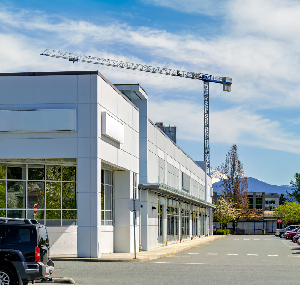Modern commercial building with parking lot and construction crane