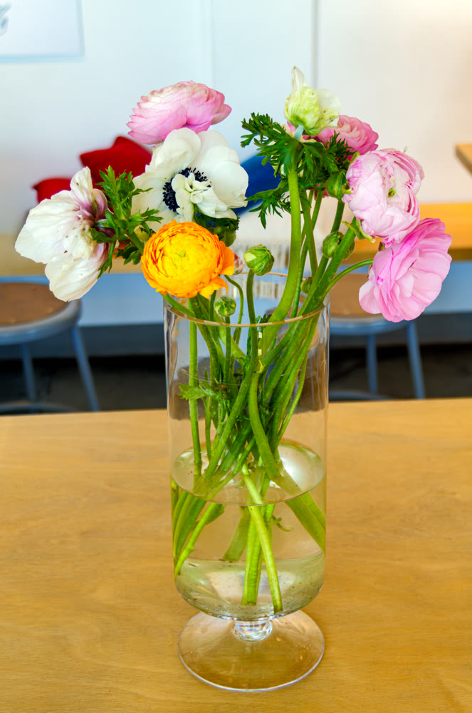 Colorful ranunculus and anemone bouquet in a glass vase on a table