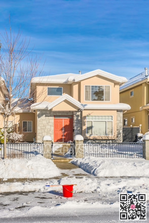 Residential duplex house in snow with red bucket on the road in front
