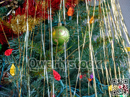 Green ornamental bauble with decorative lights among the chistmas tree brenches