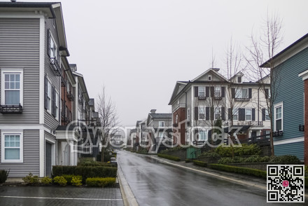 Road with new residential townhouses on cloudy rainy day