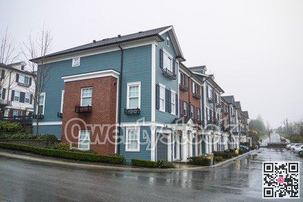 Road with brand new residential townhouses on rainy cloudy day