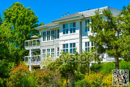 Top of luxury apartment building with green trees in front.