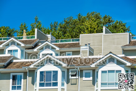 Top of residential townhouses on blue sky background.