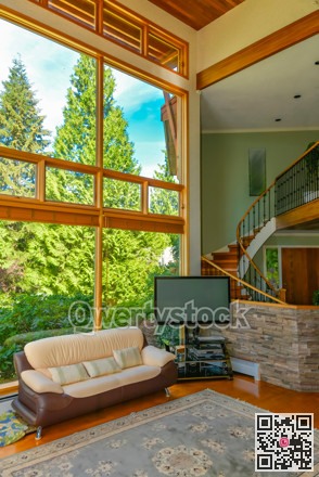 Leather couch and TV set in front of huge window in living room