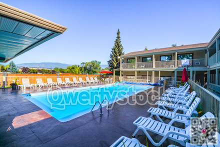 A hotel swimming pool with chaise-longues on side.